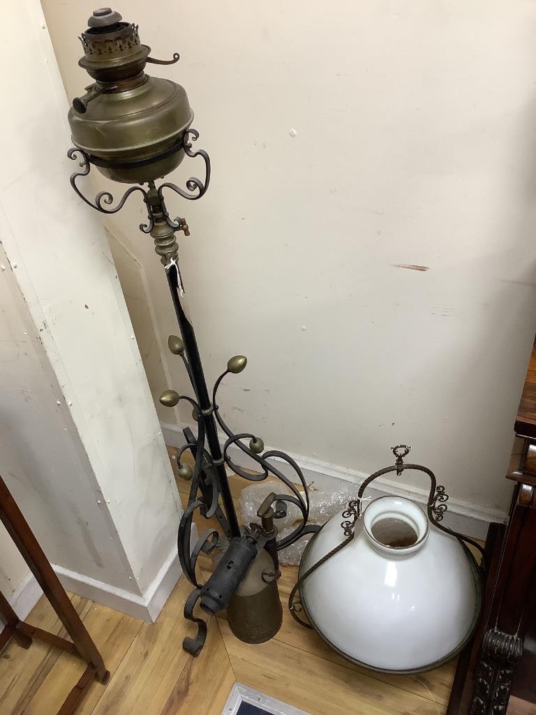 A wrought iron oil-fired floor lamp with reservoir and chimney a hanging Aladdin oil lamp with chimney and shade, and a large vintage brass blow-lamp